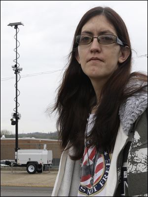 In this Thursday, April 11, 2013 photo, Holly Calhoun stands across the street from a tower of speed cameras located near the Elmwood Quick Stop she manages, in Elmwood Place, Ohio. Calhoun doesn't believe the speed cameras installed in the village were about safety. (AP Photo/Al Behrman)