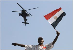 An military helicopter flies over an protester of Egyptian Islamist President Mohammed Morsi as he waves a national flag, in Tahrir Square in Cairo, Egypt.