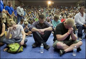 Mourners bow their heads in prayer during a memorial service, Monday in Prescott, Ariz. The service was held for the 19 Granite Mountain Hotshot Crew firefighters who were killed Sunday, when an out-of-control blaze overtook the elite group.