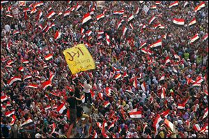 Opponents of Egypt's Islamist President Mohammed Morsi protest as they shout slogans and wave national flags in Tahrir Square in Cairo, Egypt, today. Arabic reads, 