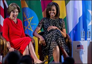 U.S. first lady Michelle Obama, right, and former U.S. first lady Laura Bush laugh as they participate in the African First Ladies Summit: “Investing in Women: Strengthening Africa,” hosted by the George W. Bush Institute today in Dar es Salaam, Tanzania.