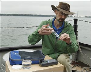 Dr. Rick Stumpf, of NOAA, demonstrates how to measure water samples with a fluorometer while on a boat in Lake Erie at Stone Laboratory on Put-in-Bay.