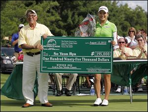 Jamie Farr presents So Yeon Ryu with a ceremonial check after she won the Jamie Farr Toledo Classic last year. Farr, who turned 79 on July 1, has had his name associated with the tournament since it began in 1984.