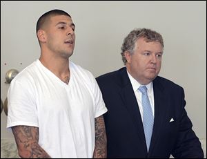 Aaron Hernandez, left, stands with his attorney, Michael Fee, right, during arraignment in Attleboro District Court in Attleboro, Mass.