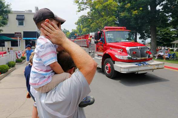 Justin-Severino-Eastlake-Ohio-covers-the-ears-of-his-son-Max-2-as-a-fire-truck-roars-past-during-a-Salute-to-America-Parade