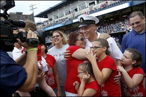 Chief Petty Officer David Schuster, center, is hugged by his mother, Pat Ricard of Berkey, as he is welcomed home by his extended family at Fifth Third Field.