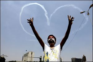 An Egyptian protester flashes v signs as military aircraft formed heart-shaped trails in the sky over Tahrir Square in Cairo on Friday.  Clashes erupted when masses of Morsi supporters tried to enter Liberation Square.