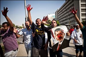 Islamist protesters, one holding a picture of ousted president Mohammed Morsi, hold up blood-stained hands after troops opened fire on a protest.