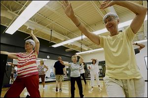 Barbara Laraway, left, Colleen Fisher, center, and Marilyn Hom stretch during a Tai Chi class.
