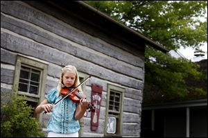 Jane Eby, 10, of Whitehouse practices outside before competing in the fiddling competition at Sauder Village in Archbold.  
