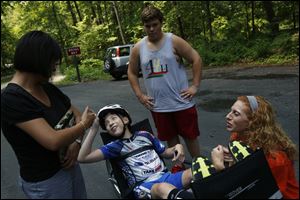 Blake Walters, 13, center left, jokes with his mother, Renata Walters, left,  during practice on his tandem recumbent bicycle at Oak Opening Preserve Metropark on Friday.  Stephanie Morrill of Programs to Educate All Cyclists, right, adjusts Blake's restraints. Her son, Skyler Canizales, 12, looks on.