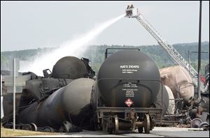 Fire fighters keep watering railway cars the day after a train derailed causing explosions of railway cars carrying crude oil Sunday in Lac Megantic, Que.