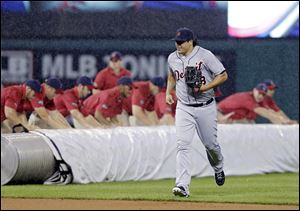 Detroit left fielder Matt Tuiasosopo runs for the dugout as the grounds crew rolls out the tarp in a rain delay in the second inning in Cleveland. Tuiasosopo hit a home run in the fourth inning.
