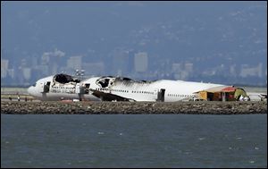 The wreckage of Asiana Airlines Flight 214 that crashed upon landing Saturday at San Francisco International Airport sits on the tarmac Monday, July 8, 2013 in San Francisco. Investigators said the Boeing 777 was traveling 