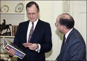 President George H.W. Bush, shown in this 1990 photo, jokes with Arthur Shorin, president of Topps Co., Inc., after Shorin presented him a book of baseball cards. The cards depicting the former president as a Yale first baseman have fetched thousands of dollars.