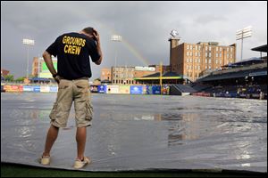 Christopher Chapinski helps hold down the tarp during a rain delay at Fifth Third Field in Toledo.