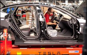 An employee works on a Telsa Motor Inc. Model S sedan as it makes its way along an assembly line at company's assembly plant in Fremont, Calif., Wednesday.
