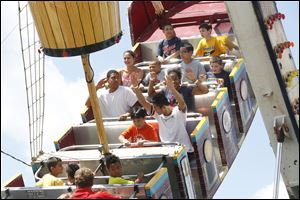 Ron Ou, 18, of Sylvania, center right, raises his hands as he tries to coax his brother, Jerry Ning, 9, to do the same while riding ' The Sea Ray' at the Lucas County Fair in Maumee. The brothers spent the day together at the fair, which enjoyed its first rain-free day of the week on Thursday.