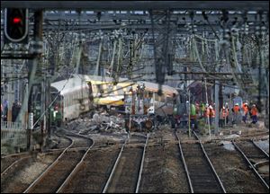Railways workers are seen at the site where a train derailed Friday, at a station in Bretigny-sur-Orge, south of Paris, today.