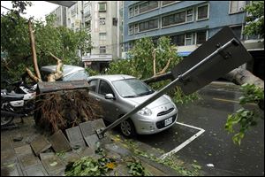 Fallen trees damaging vehicles lie on a street after Typhoon Soulik hit Taiwan early today in Taipei. 