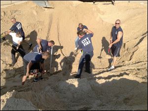 FILE - In this July 12, 2013 file photo, Michigan City police and firefighters dig with shovels to rescue Nathan Woessner, of Sterling, Ill., who was trapped for more than three hours under about 11 feet of sand at Mount Baldy dune near Michigan City, Ind. On Monday, July 15, the doctor who helped treat the 6-year-old boy says the child is expected to make a full neurological recovery. (AP Photo/Michigan City Fire Department via The News Dispatch, File)
