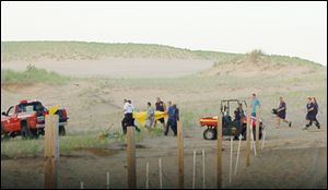 In this July 12, 2013, photo rescue workers with a stretcher carrying 6-year-old Nathan Woessner after he was pulled from a sand dune at the Indiana Dunes National Lakeshore in Michigan City, Ind. Doctors said Monday, July 15, that the boy, who was buried for hours the sand dune, is responsive and expected to make a full neurological recovery. (AP Photo/The News Disparch, Julie McClure)