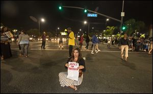 A demonstrator with a sign sits on the intersection of Crenshaw Boulevard and Coliseum street during a protest in Los Angeles on Sunday, July 14, 2013, the day after George Zimmerman was found not guilty in the shooting death of Trayvon Martin.