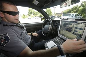 Office Dennis Vafier of the Alexandria Police Dept., uses a laptop in his squad car to scan vehicle license plates during his patrols.