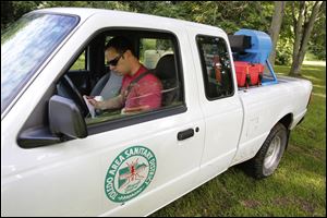 Myles Caryer of Toledo Area Sanitary District Mosquito Control checks his next stop after spraying for mosquitoes on Wolfinger Road.