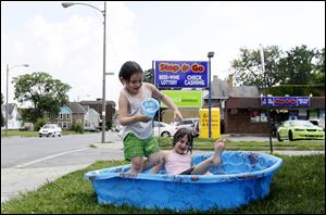  Kristianna Reno, 4, left, and Riley Funk, 6, try to cool off at East Broadway and Mason Street in East Toledo. Humidity is helping high temperatures feel hotter.