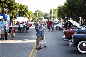 Sue Rioux, 73, of North Toledo, center right, points to one of the classic cars her grandson, Patrick Rioux, 14, is photographing as the pair peruse the selection during the event Taking it to the Streets on Thursday.