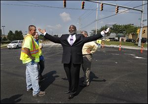 Mayor Mike Bell, while greeting street workers after a news conference at Secor Road and Central Avenue, lifts his arms and proclaims, 'It's rare a mayor can stand in the middle of an intersection!'  At left is Matt Mikolajczyk, a construction technician for the city.