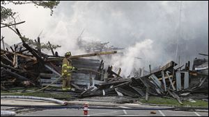 A Springfield Township firefighter works the scene of the fatal fire at the Hidden Cedars Condominiums on Garden Road in Springfield Township on March 26, 2012.