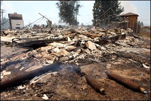 What remains of a home destroyed by the Mountain Fire smolders Tuesday in Pine Springs Ranch, Calif.
