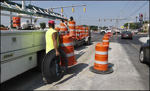 Construction workers remove orange barrels from the Secor Road-Central Avenue intersection that reopened on Friday.