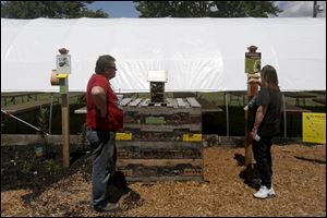 Kim McCance, of Weston, right, and a man who declined to be named, left, read up on the insect hotel outside the Horticulture Barn.