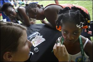 Deja Williamson of West Toledo, center left, listens to the live music at the festival as her friend Joy Fullilove, center, jokes with her son Mark Smith, 9, both of West Toledo.