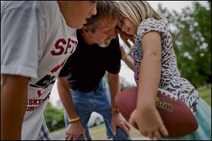 David Schooley, 57, center, huddles with his children, Nathaniel, 12, and Hannah, 6, while playing football in his front yard.