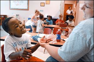Charlie Sarver, 6,  laughs as his teacher, Erika Henson cleans paint off his hands after working on an art project in the Prescribed Pediatric Center, a section devoted to children with disabilities.