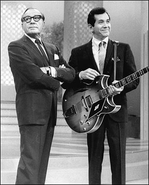 Comedian Jack Benny was known as a master of comic timing.  This was the expression that accompanied his famous ‘Hmm-m-m.’ Here he's inflicting it on singer-guitarist Trini Lopez in November, 1966.