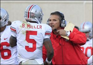 Ohio State head coach Urban Meyer talks with quarterback Braxton Miller (5) during the fourth quarter of an NCAA college football game against Michigan State at Spartan Stadium in East Lansing, Mich., Saturday, Sept. 29, 2012.  Ohio State held off No. 20 Michigan State 17-16 giving Urban Meyer a win in his first Big Ten game as Buckeyes coach. (AP Photo/Carlos Osorio)