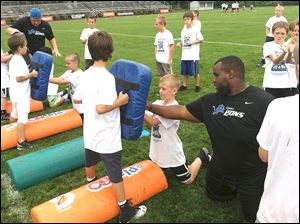 Patrick Hill, instructor for the Detroit Lions Youth Football Camp instructs Dyson Hall, 10, on offensive line blocking. 