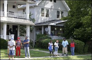 East Cleveland residents watch the scene, Sunday, close to where three bodies were recently found.