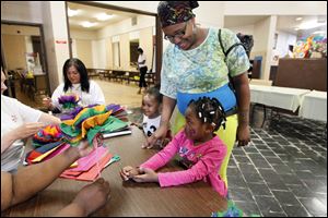 Ashley Fowlkes, center, helps her children Krystal Morris, 3, left, and Myanna Morris, 4, right, with crafts after registering them for Head Start at the J.B. Simmons Community Center in May.
