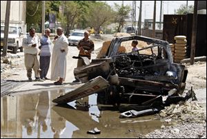 Civilians inspect the aftermath of a car bomb attack in Baghdad, Iraq, Wednesday, July 24, 2013. A bomb exploded near a Sunni mosque in Baghdad's southern Dora neighborhood on Tuesday, killing several people and wounding many more,  police said.