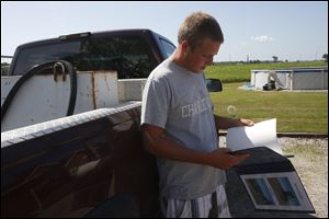 Trevin Haar, 17, looks at his crop listing after retrieving the binder from his truck at his home in Woodville. 