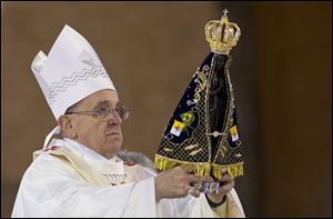 Pope Francis holds up the statue of the Virgin of Aparecida, Brazil's patron saint, during Mass in the Aparecida Basilica in Aparecida, Brazil, Wednesday.