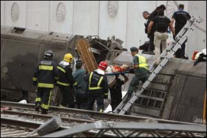 A woman is evacuated by emergency personnel at the scene of a train derailment in Santiago de Compostela, Spain.