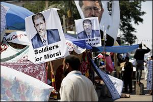 A supporter of Egypt's Islamist President Mohammed Morsi in front pictures of the ousted president.