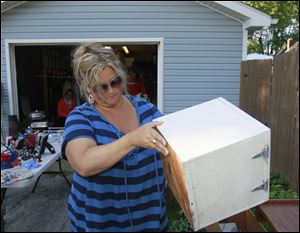 Raechel Kolling checks out a square wooden box at a west Toledo garage sale. Kollig re-creates the items she buys into trendy merchandise for her shop, The Green Boutique.